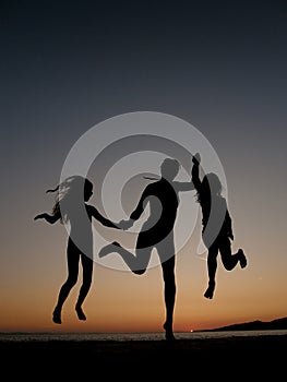 Woman and girls jumping in sunset