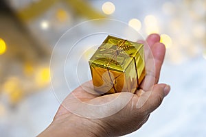 woman give of a Christmas golden colors gifts box compliments concept in a holiday-bokeh background