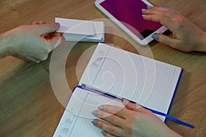 A woman gives a business card to a client. Notepad and tablet in the background on a wooden office table