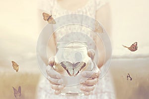 Woman gives freedom to some butterflies enclosed in a glass vase