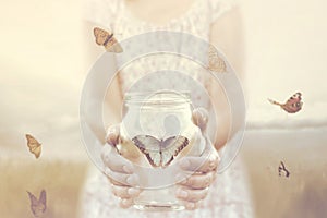 Woman gives freedom to some butterflies enclosed in a glass vase photo