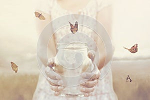 Woman gives freedom to some butterflies enclosed in a glass vase