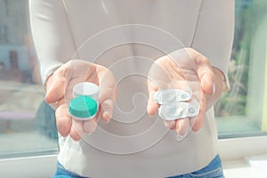 The woman gives in the hands of one-day contact lenses and reusable contact lenses. choosing the type of contact lenses