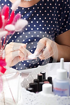 A woman gives herself a manicure. Removes old nail Polish with a nail buff. Next to a set of lacquers, tools and a bouquet of