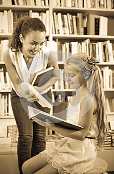 Woman giving book to girl in school age in bookstore