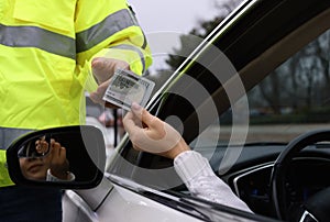 Woman giving bribe to police officer out of car window, closeup