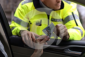 Woman giving bribe to police officer out of car window, closeup