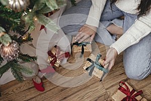 Woman giving christmas gift under christmas tree in festive decorated room close up. Merry Christmas and Happy Holidays! Couple