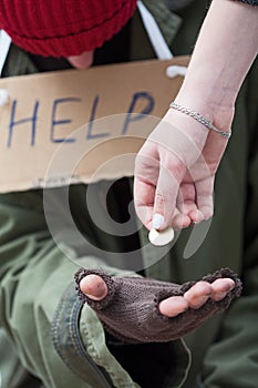 Woman giving a coin to homeless man