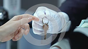 Woman giving dollars and receiving key from suite or spa center locker, hotel