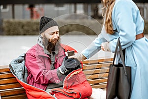 Woman giving a drink to a homeless beggar