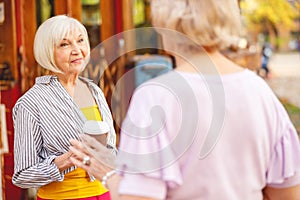 Woman giving her friend a cup of coffee