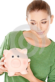 Woman giving her piggy bank a speculative look