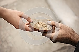 Woman giving poor homeless person pieces of bread outdoors