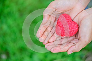 Woman giving red heart on green grass background