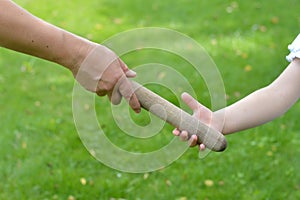 Woman giving the relay baton into a child`s hand