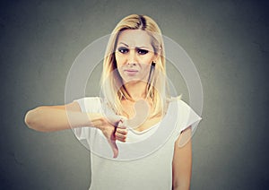 Woman giving thumb down gesture looking with negative expression and disapproval