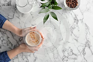 Woman with glass of aromatic hot coffee at marble table,