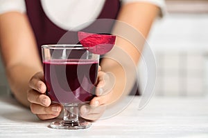 Woman with glass of beet smoothie at table