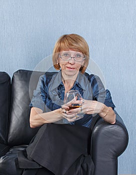 Woman with a glass brandy on couch