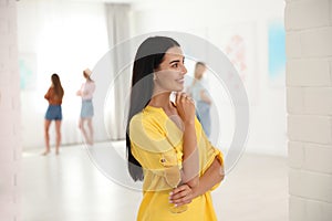 Woman with glass of champagne at exhibition in art gallery