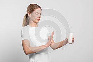 Woman with glass of milk suffering from lactose intolerance on white background