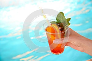 Woman with glass of refreshing drink near swimming pool. Space for text