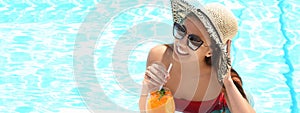 Woman with glass of refreshing drink in swimming pool on sunny day, banner design