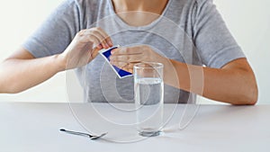 Woman with glass of water opening pack of medicine