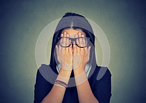 Woman in glasses covering face eyes using her both hands