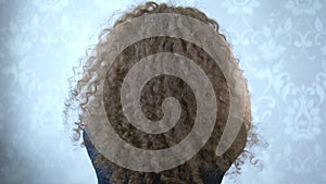 Woman in glasses with curly hair twirls her head, the wind in her hair