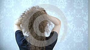 Woman in glasses with curly hair twirls her head, the wind in her hair