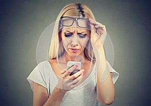 Woman with glasses having trouble seeing cell phone has vision problems. Confusing technology