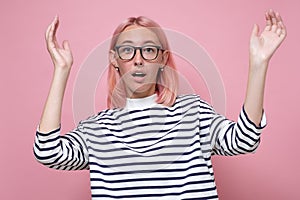 Woman in glasses looking with disbelief at camera holding hands up