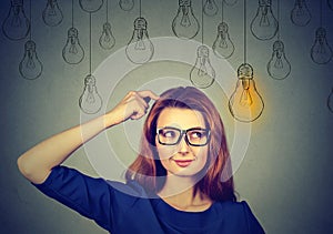 Woman in glasses looking up light idea bulb above head