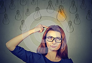 Woman in glasses looking up with light idea bulb above head