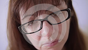 Woman with glasses looks with an accusingly scrutinizing look, close up