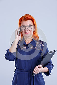 Woman in glasses on the phone with tablet hands on a gray background