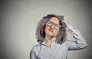 Woman with glasses scratching head, thinking confused