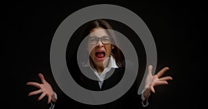 Woman with glasses, shouting with an aggressive expression and raised hands.