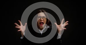 Woman with glasses, shouting with an aggressive expression and raised hands.