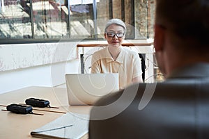 Woman in glasses sitting across table from a man