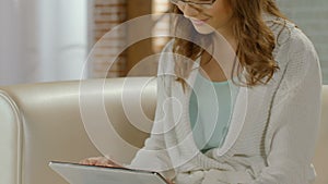 Woman in glasses sitting with tablet and typing, smart girl, working on project