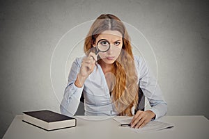 Woman with glasses skeptically looking at you through magnifying glass
