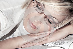 Woman with glasses sleeps on book