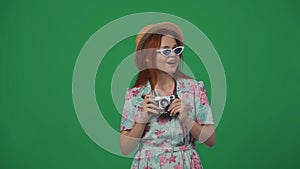 Woman in glasses and straw hat holding old film camera, looking around with amazed happy face expression. Isolated on