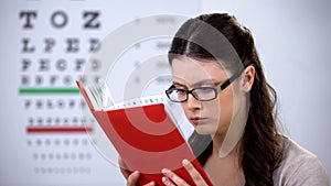 Woman in glasses suffering myopia reading book, need in correct lens diopter