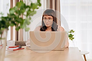 Woman in glasses using laptop for remote work or watching webinar