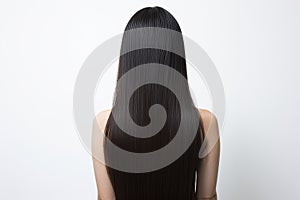 Woman with glossy brunette hair from behind, white backdrop