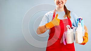 Woman in gloves and apron holding basket with sponge and cleaning products